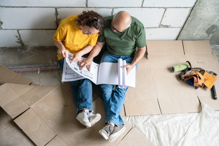 Un couple examine des plans de construction sur un chantier – image symbolique illustrant la conception du plan d'une maison et de la répartition des pièces.