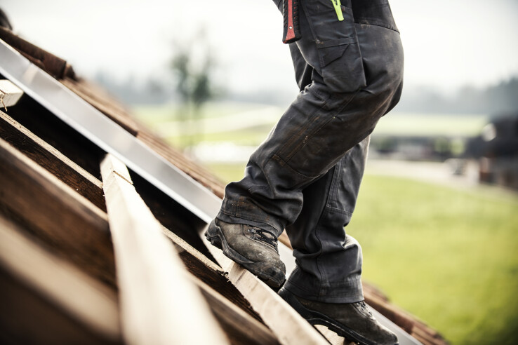Un artisan travaille sur le toit d'une maison pendant des travaux de rénovation.