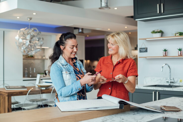 Dans une cuisine moderne, deux femmes discutent des échantillons de matériaux pour l'aménagement de la cuisine.