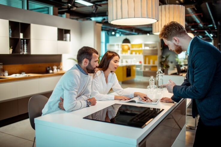 Un couple conçoit ensemble une nouvelle cuisine avec l'aide d'un professionnel de la cuisine