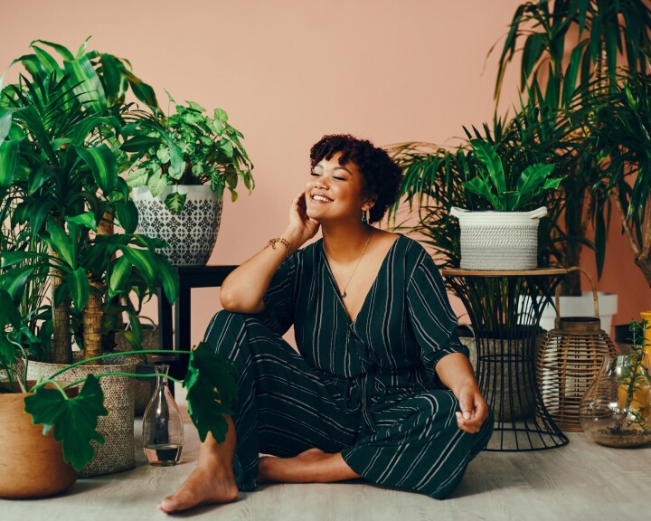 Une femme est assise au milieu de ses plantes d'intérieur