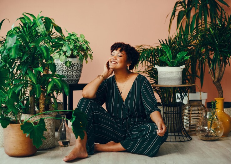 Une femme est assise au milieu de ses plantes d'intérieur