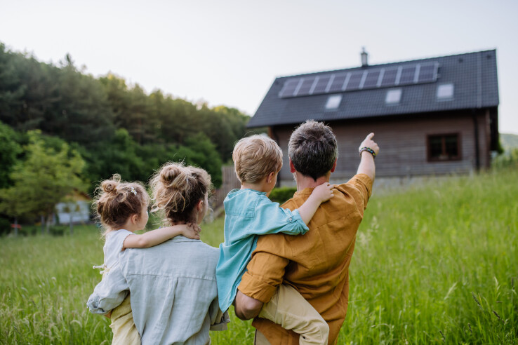 Une famille se tient devant sa maison équipée d'un nouveau système solaire