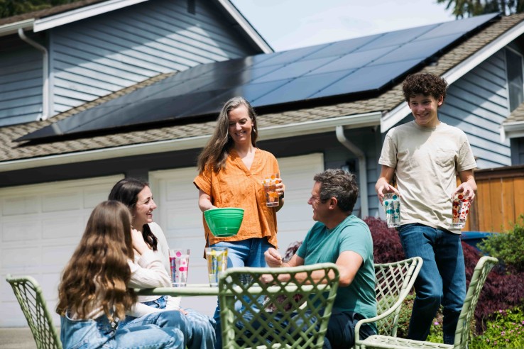 RCP virtuel : des voisins se retrouvent devant un immeuble équipé d'une installation photovoltaïque et partagent l'électricité solaire produite localement.