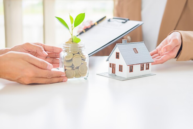 Energetische Sanierung: Hausmodell und Sparglas symbolisieren die Wertsteigerung eines Eigenheims.