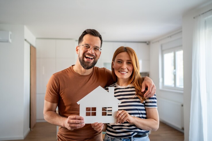 Un couple souriant prévoit de rembourser son prêt immobilier pour leur maison.