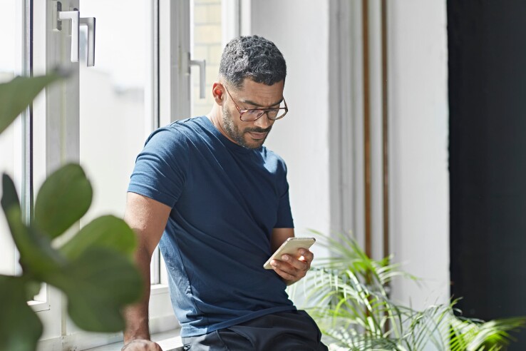 Une personne utilise un smartphone chez elle et se renseigne sur la pollution électromagnétique et les rayonnements.