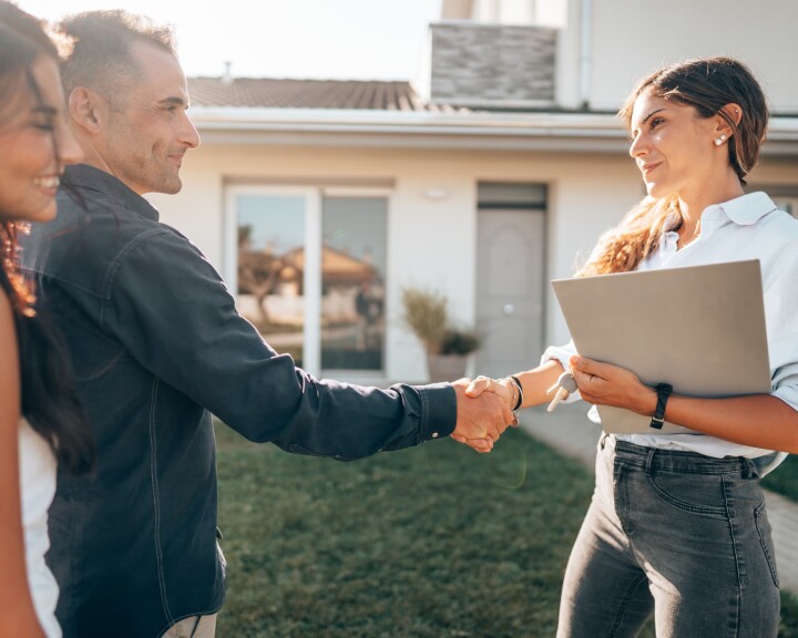 Après avoir conclu avec succès la vente d'une maison, une agente immobilière serre la main du propriétaire immobilier.