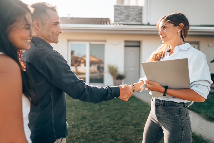 Après avoir conclu avec succès la vente d'une maison, une agente immobilière serre la main du propriétaire immobilier.
