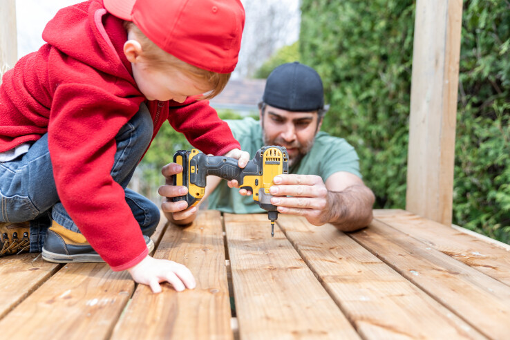 Un père et son enfant construisent ensemble une terrasse en bois – image symbolique d'un projet de construction pouvant faire l'objet d'un permis de construire en Suisse.