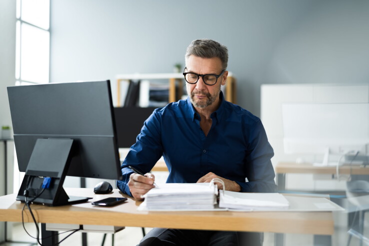 Un homme assis à une table avec des documents, image illustrative du calcul du quota de valeur dans la copropriété.
