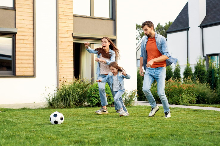 Une famille joue au football dans le jardin d'un appartement avec jardin – illustration symbolique du droit d'usage exclusif dans la copropriété.
