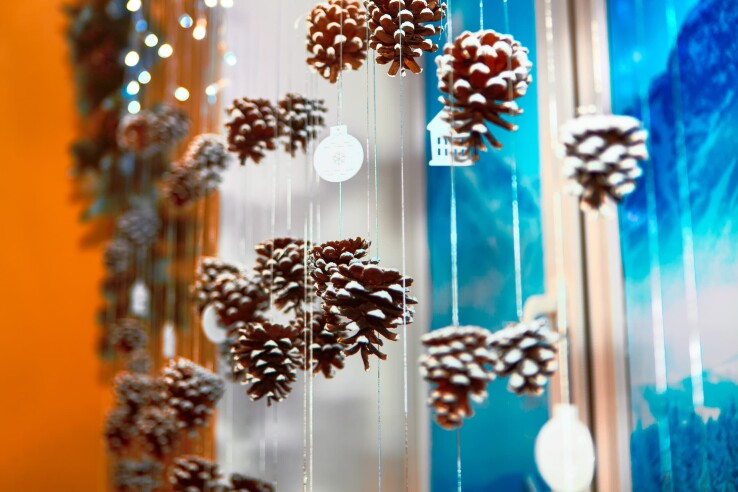 Fenêtre de l’Avent décorée de pommes de pin suspendues aux accents hivernaux.