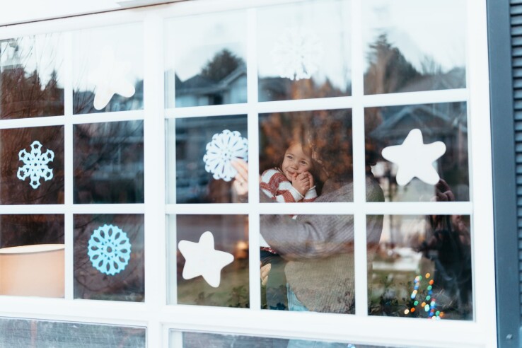Fenêtre de l’Avent décorée d’étoiles et de flocons de neige blancs collés par des enfants.