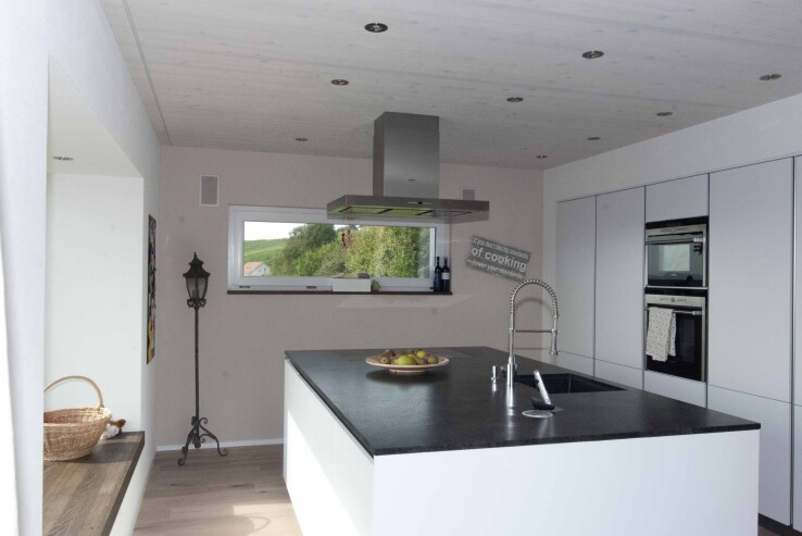 Reportage architectural à Nussbaumen Feng Shui : la cuisine est équipée d'un grand îlot de cuisine