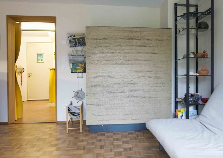 Un poêle à accumulation en terre battue, pièce maîtresse du nouveau système de chauffage dans le salon et la salle à manger d'une maison mitoyenne rénovée.