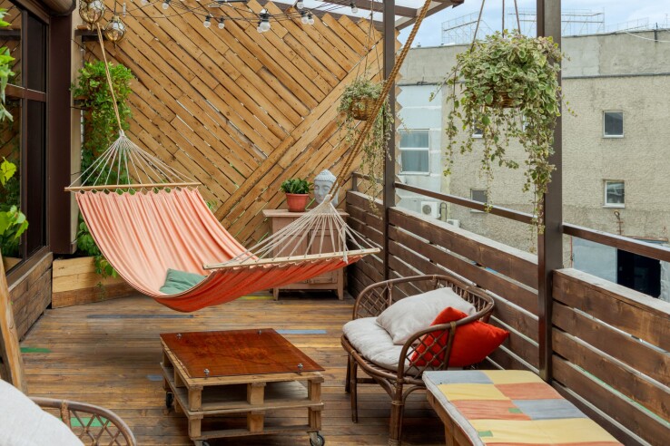 Gemütlich eingerichtete Terrasse mit Hängematte, Sitzmöbeln und hängenden Pflanzen.