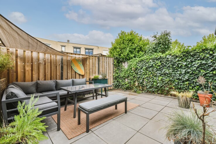 Moderne Terrasse mit Lounge-Möbeln, Sichtschutz aus Pflanzen und Kletterpflanzen an der Grundstücksgrenze.