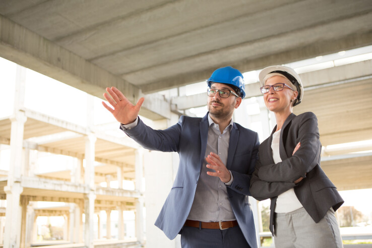Un conseiller en construction accompagne une maîtresse d'ouvrage dans la planification d'un projet de construction.