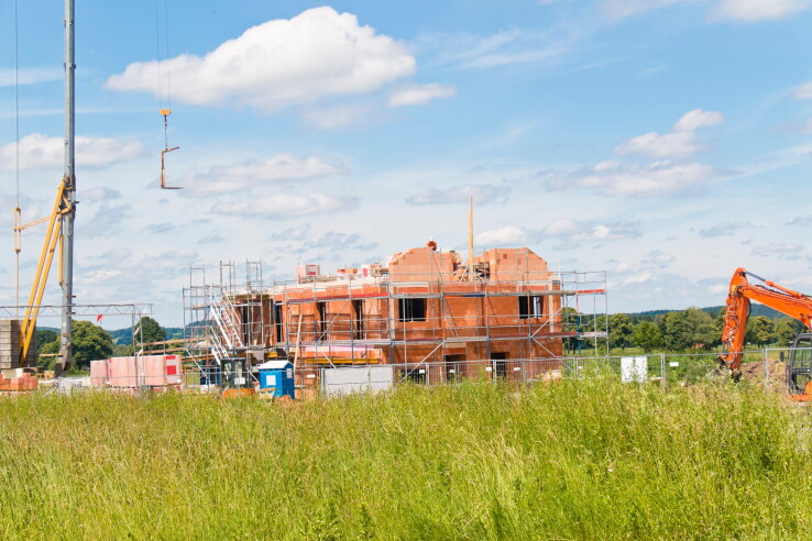 Nouvelle construction sur un terrain à bâtir, avec une grue de chantier et un échafaudage pendant la phase de gros œuvre.