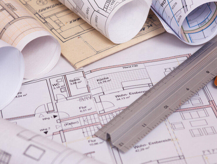 Des plans de construction et des plans d'étage à l'échelle, qui symbolisent les contrôles de construction et le travail de la police du bâtiment.