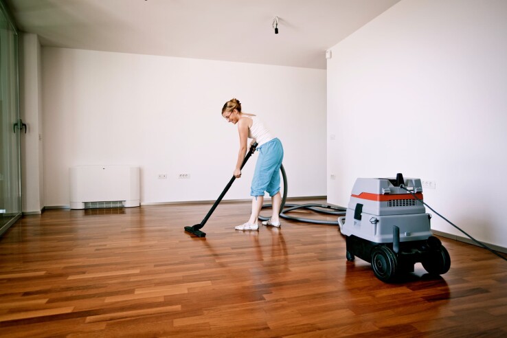 Après la construction de sa maison, une personne nettoie son nouveau parquet à l'aide d'un aspirateur industriel.
