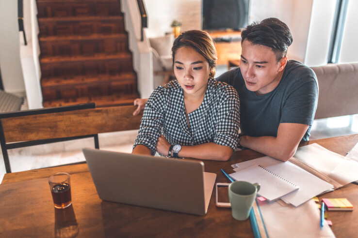Un couple prépare un dossier de candidature pour l'achat d'une maison.