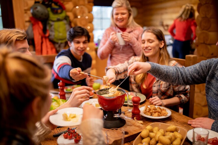 Une famille déguste une fondue au fromage avec un réchaud à fondue à table.