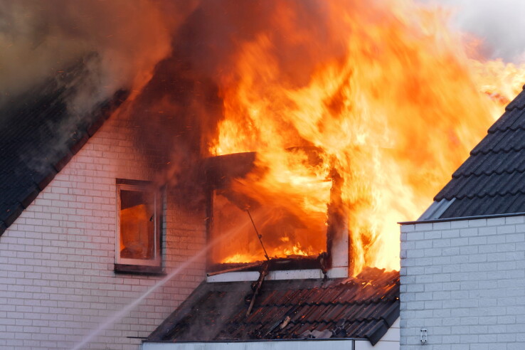 Une maison individuelle en feu avec un important dégagement de fumée – image symbolique illustrant la sécurité incendie et les règles de sécurité incendie applicables aux habitations.