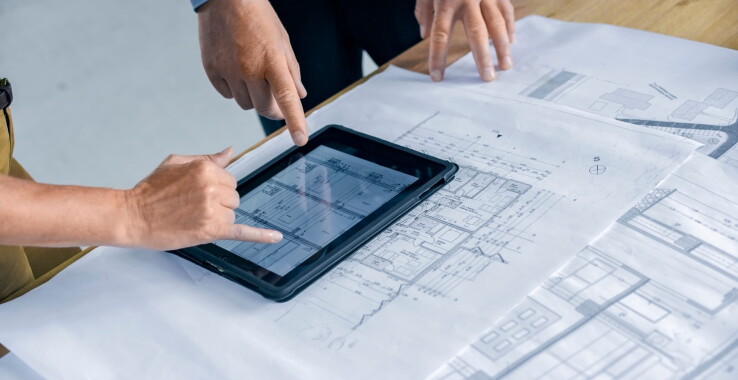 Des experts examinent les plans de construction ainsi qu'un plan numérique du bâtiment afin de vérifier la conformité aux normes de sécurité incendie lors de la construction d'une maison.