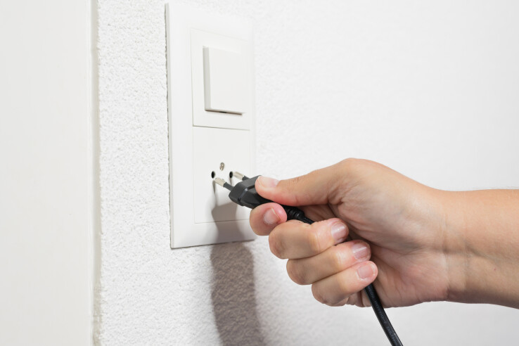 Une main branche une fiche secteur dans une prise – utilisation sûre de l'électricité à la maison.