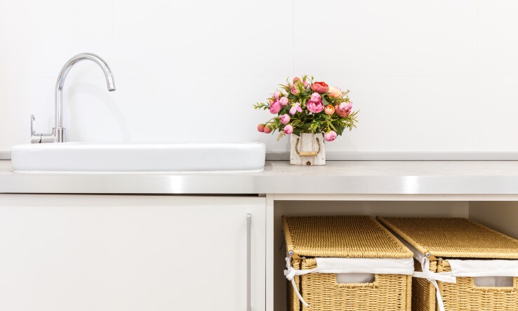 Salle de bains avec lavabo, bouquet de fleurs et deux paniers de rangement sous le meuble-lavabo.