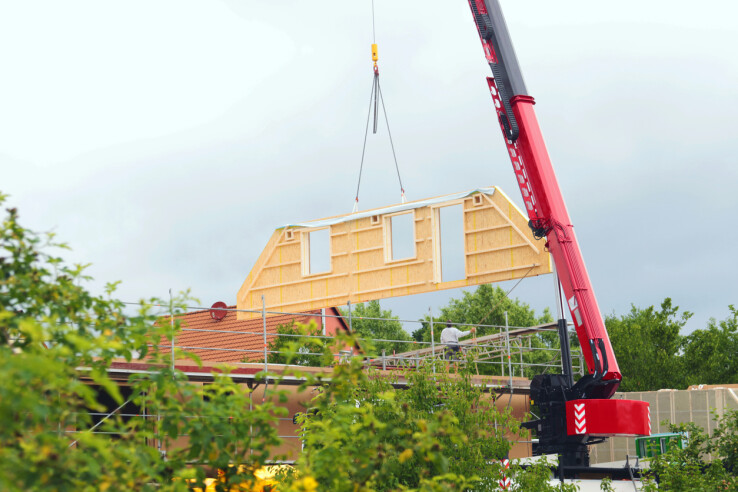 Construction d'une maison à l'aide d'une grue : montage d'un élément de construction en bois – construction parasismique en Suisse
