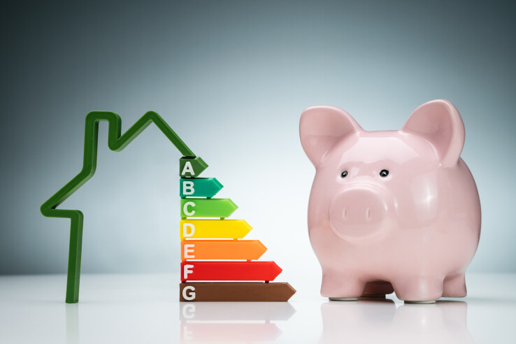 Une tirelire et une étiquette énergétique symbolisent les aides financières destinées à la rénovation énergétique des bâtiments.