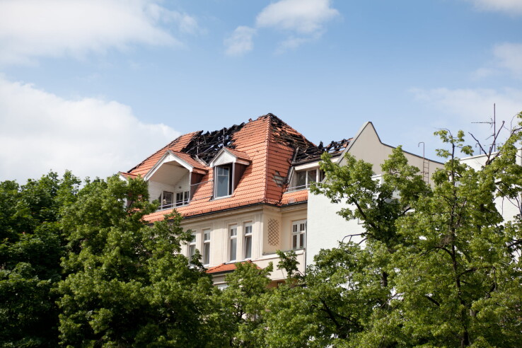 Une maison d'habitation dont le toit a été endommagé par un incendie, illustrant l'importance de la valeur d'assurance du bâtiment en cas de sinistre.