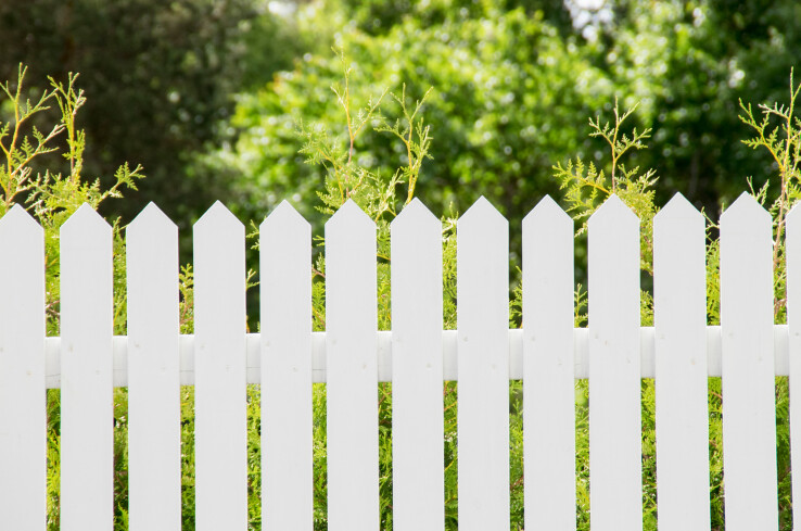 Une clôture de jardin entre deux parcelles illustre les distances à respecter par rapport aux limites de propriété pour les constructions et les plantations.