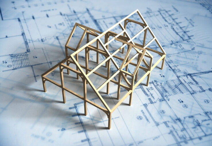 Maquette d'une maison sur des plans de construction, symbolisant l'achat d'une maison sur plan.