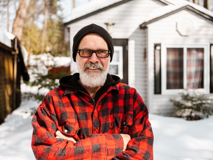 Un homme d'un certain âge devant une maison, symbole de la transmission d'un bien immobilier à l'étranger.