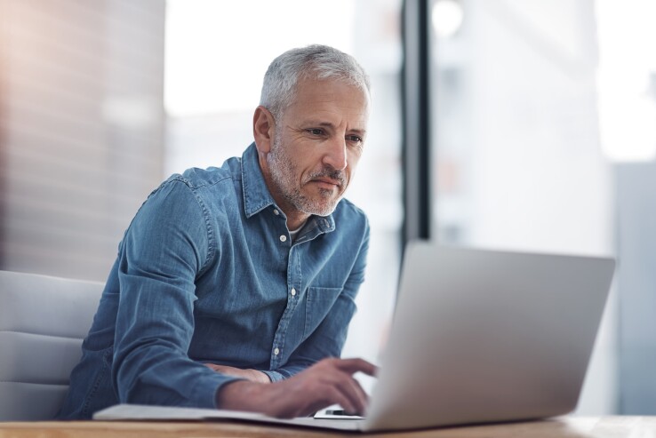 Une personne de plus de 50 ans planifie sur son ordinateur portable l'achat d'une maison et son financement pour la retraite