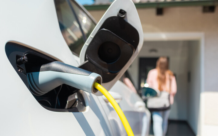 Elektroauto wird zuhause an einer Wallbox mit Ladekabel auf dem privaten Parkplatz geladen.