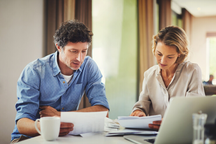 Un couple examine les documents relatifs au renouvellement anticipé d'un prêt hypothécaire et compare les taux d'intérêt ainsi que les durées d'un prêt hypothécaire à terme.
