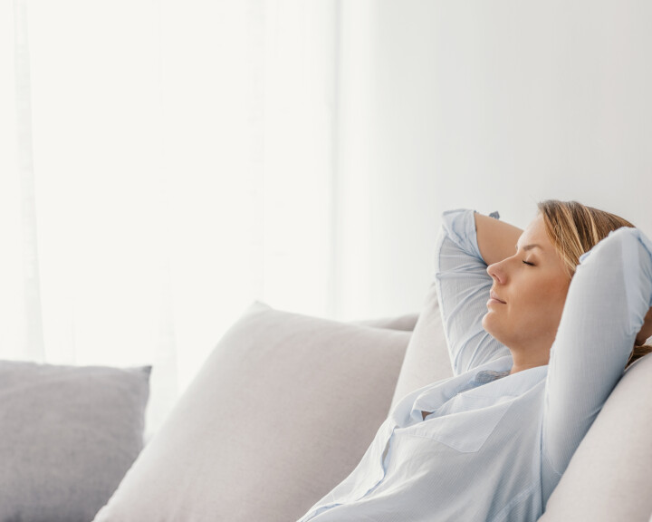 Une femme se détend sur un canapé dans un salon lumineux, où règne un climat ambiant idéal.