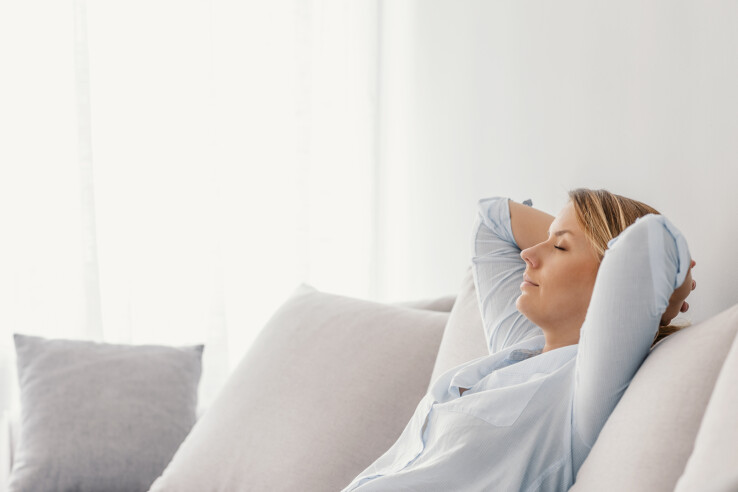 Une femme se détend sur un canapé dans un salon lumineux, où règne un climat ambiant idéal.
