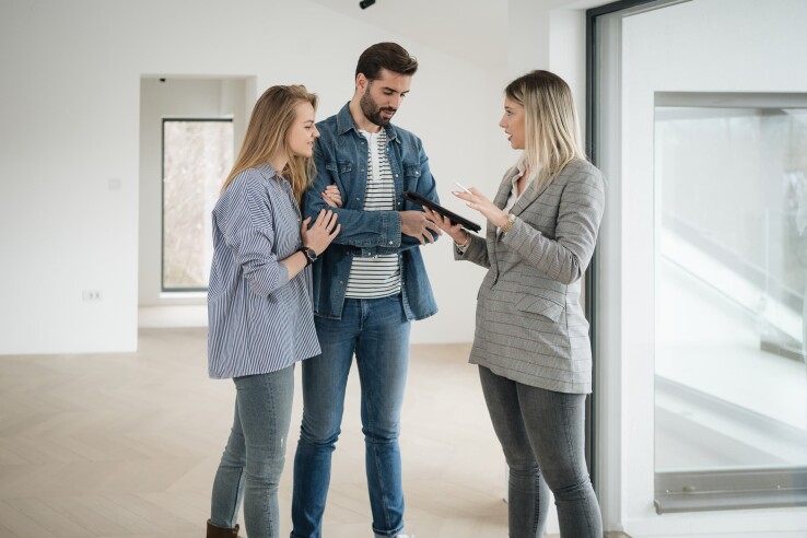 Immobilienmaklerin bespricht mit einem Paar die Vermietung einer Wohnung während einer Besichtigung.