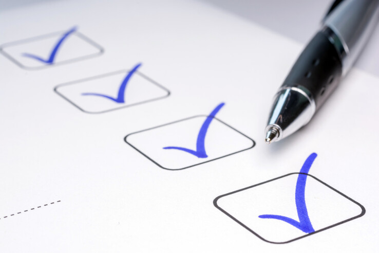 Une liste de contrôle avec des cases à cocher et un stylo à bille – illustration symbolique de la vérification d'un contrat de location.