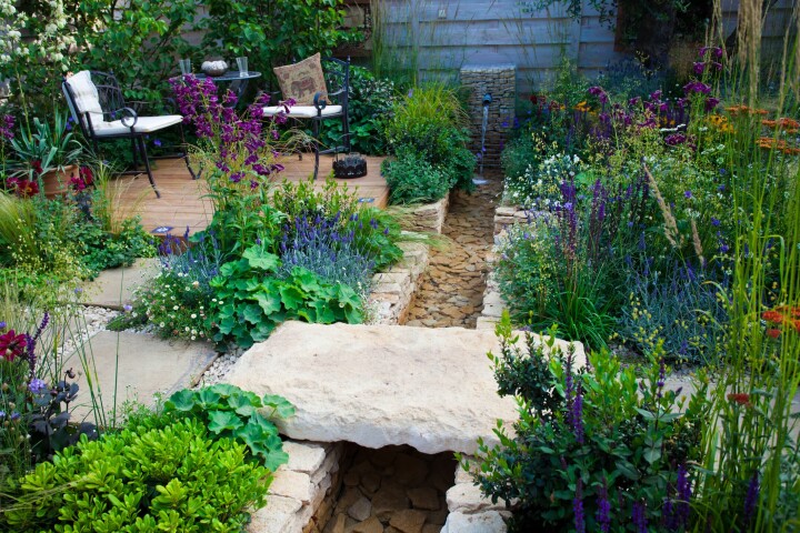 Jardin naturel avec des plantes vivaces à fleurs, un sentier en pierre naturelle et un coin détente, offrant un habitat proche de la nature aux plantes et aux animaux.