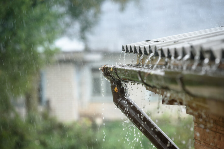L'eau de pluie s'écoule par une gouttière et est récupérée pour être utilisée dans la maison.