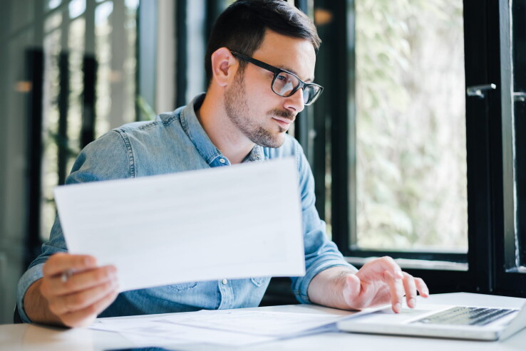 Un homme, en tant qu'organe de révision, vérifie les documents de la copropriété sur son ordinateur portable.