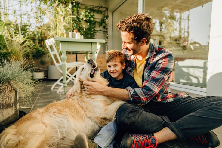 Une famille avec son chien sur la terrasse d'un appartement en copropriété – Avoir un animal de compagnie dans un immeuble en copropriété est en principe autorisé, tant que ça ne dérange pas les autres.