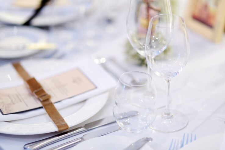 Une table dressée avec style, avec des assiettes, des couverts et des verres à vin, pour un repas de fête